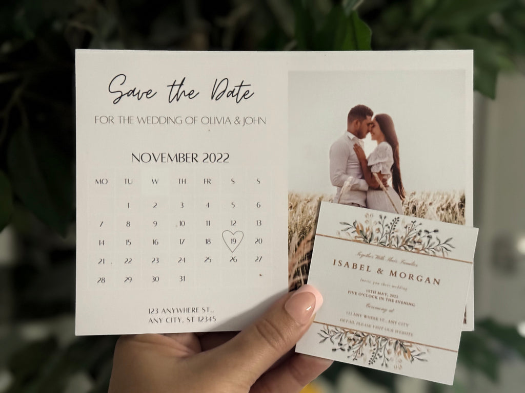 Hand holding both a standard 'Save the Date' personalized magnet with a couple and calendar for Olivia & John's wedding in November 2022 and square save the date with event information.