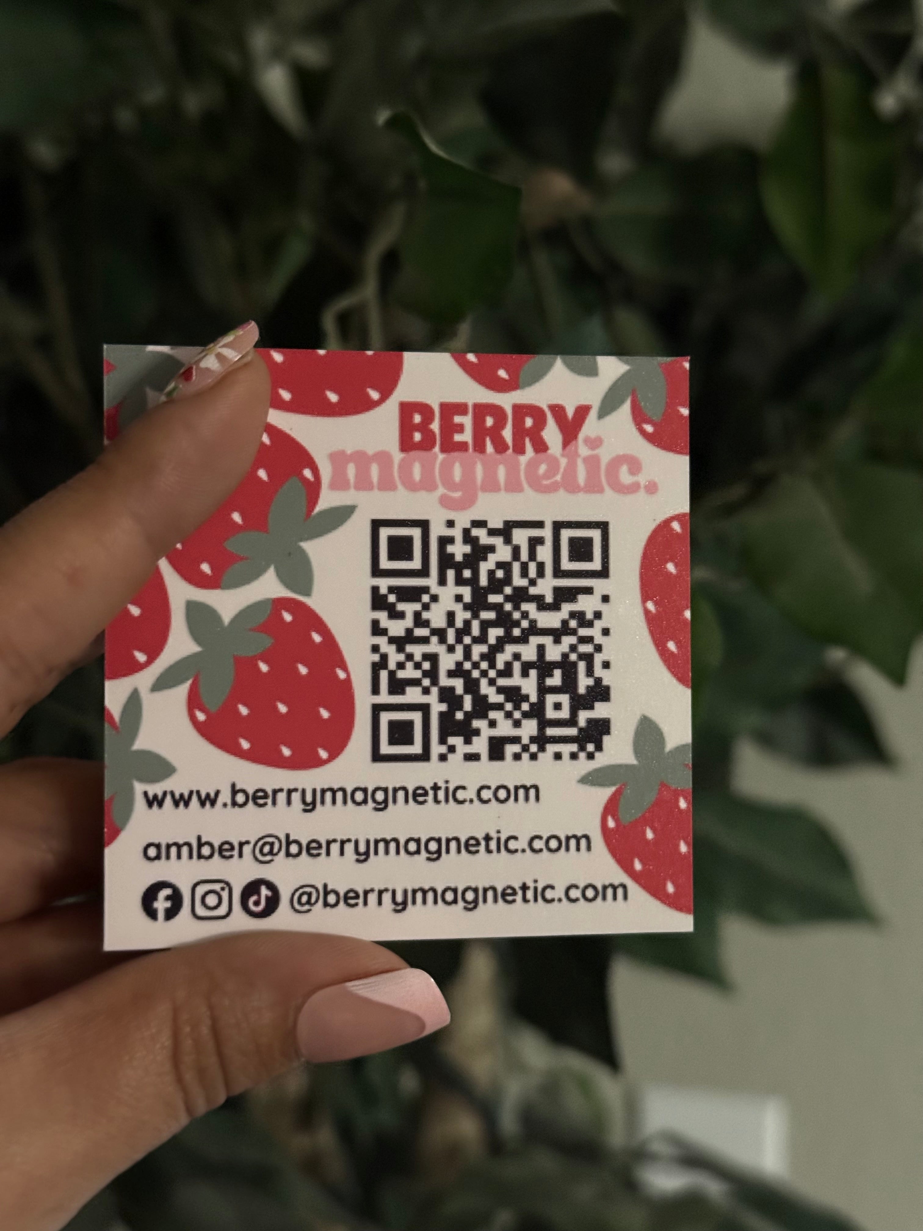 Hand holding a Berry Magnetic business card with a QR code and contact information.