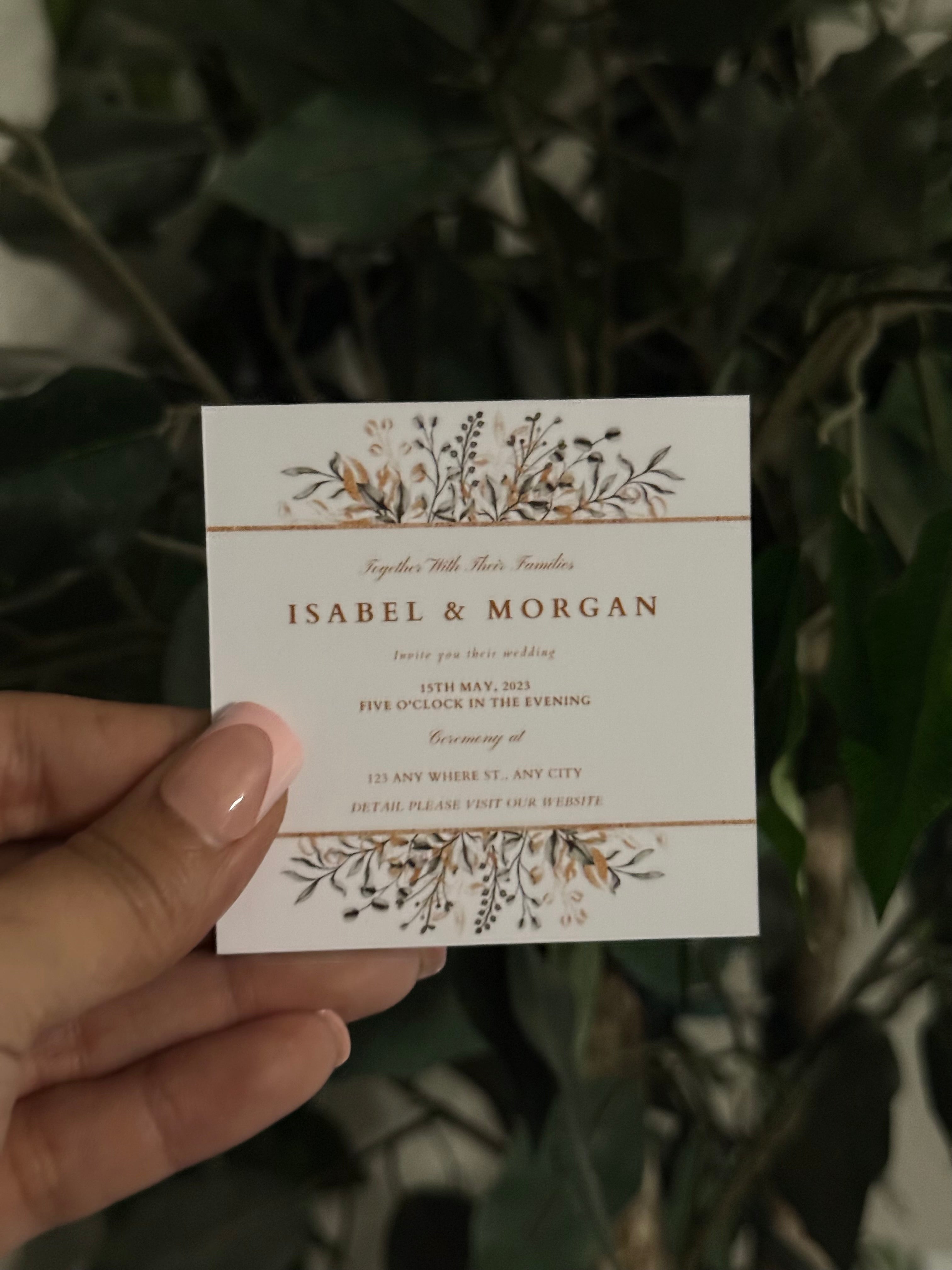 Hand holding a square personalized magnet with floral design against a leafy background